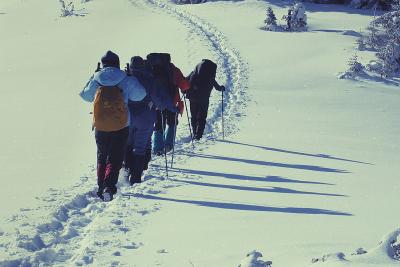 Група туристів з наплічниками піднімається стежкою на засніжену Говерлу